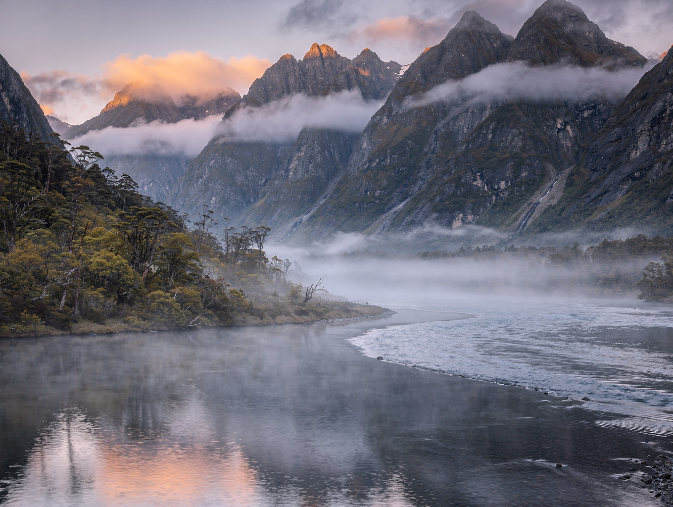 Mitre Peak reflected in still fjord waters during pink dawn mist